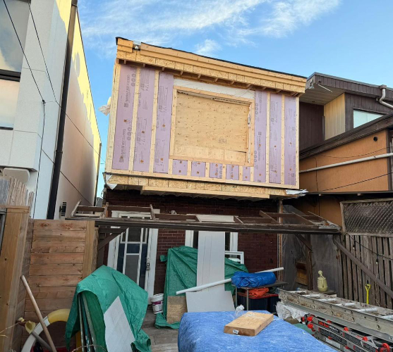 Home addition construction in Toronto with second-story framing, exterior insulation panels, and structural work in progress, part of a residential renovation project.